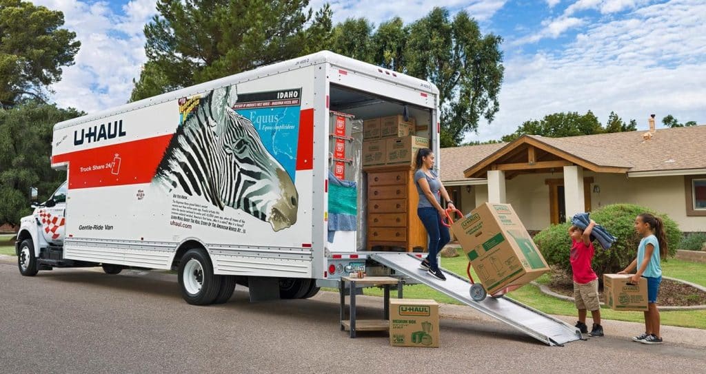image of u-haul truck being loaded by a family in front of a house