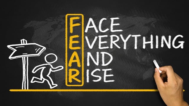 Chalkboard drawing with the acronym 'FEAR' spelled vertically, reading 'Face Everything And Rise', beside an illustration of a person running up the stairs formed by the letters, symbolizing overcoming fear.