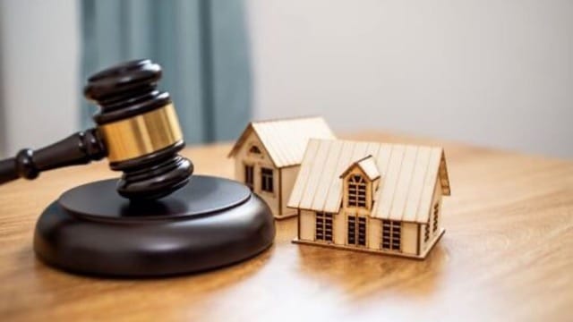 A gavel beside a model house on a desk, symbolizing legal actions for late rent payments in property management