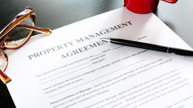 Close-up of a property management agreement with a pen, emphasizing the critical nature of understanding property management fee structures