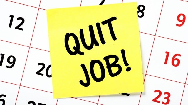 Yellow sticky note with 'QUIT JOB!' written in black marker, placed on a calendar with dates visible around it