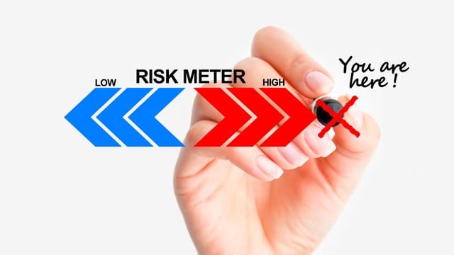 A hand marking a risk meter that ranges from low to high, highlighting the misconception that real estate investing is highly risky.