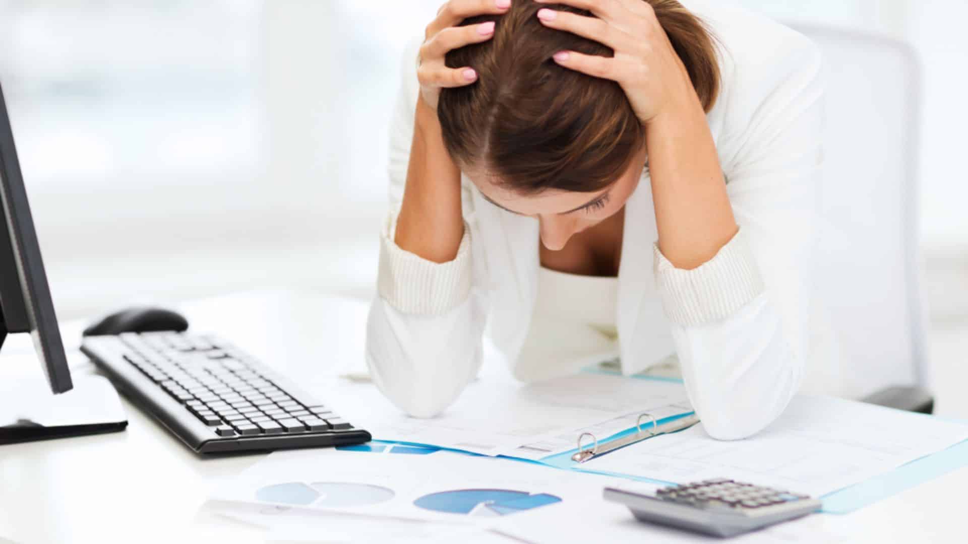 Frustrated woman at a desk with paperwork, symbolizing the stress of a property manager switch, as she considers changing management for better service