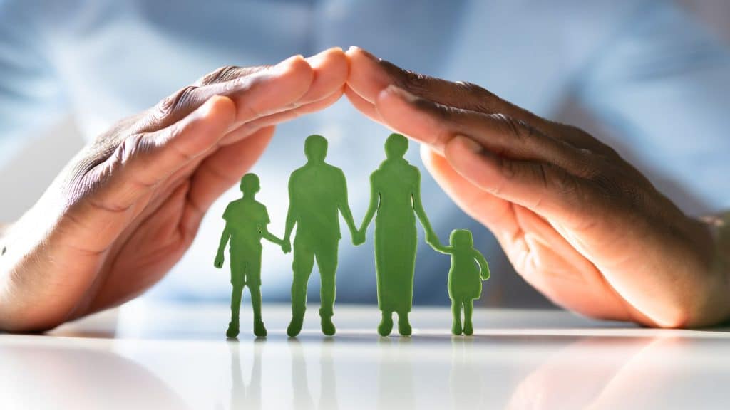 Hands forming a protective roof over a green paper cutout of a family, symbolizing the protection and security offered by renters insurance.