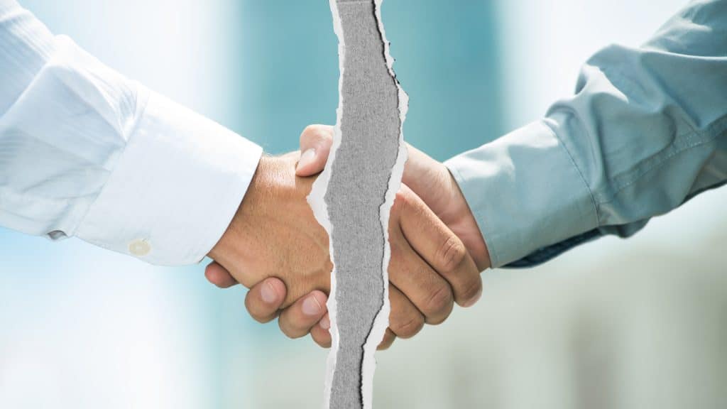 A torn handshake symbolizing the risks and challenges of real estate partnerships, highlighting the importance of trust and clear communication in investing.