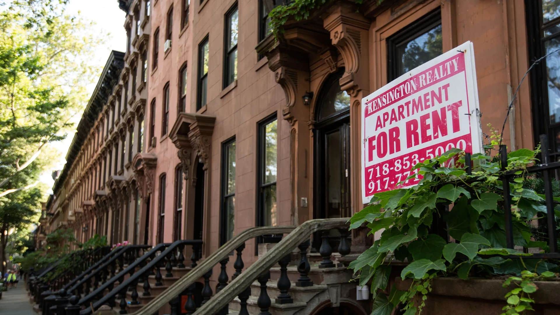 A "For Rent" sign in front of a brownstone representing the demand and opportunities in multifamily investment.